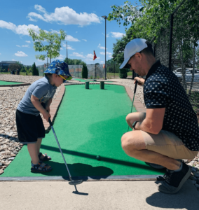 Parent and child playing mini golf while practicing their French