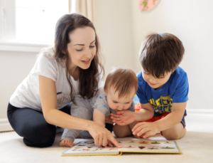 Mother (Madame Amy) and her two young children are reading a book together