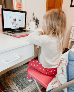 A young girl looks at the screen as she learn French during her virtual preschooler French class.