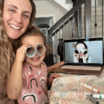 Preschooler and parent are participating in a virtual French preschooler class. The young girl is holding up a pair of DIY binoculars made as a fun craft during French class.
