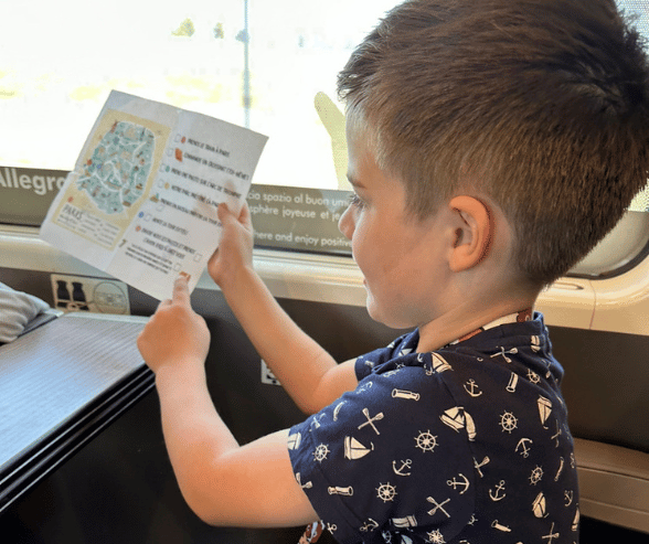 Madame Amy's son excitedly pointing to his visual itinerary while on a train to Paris.