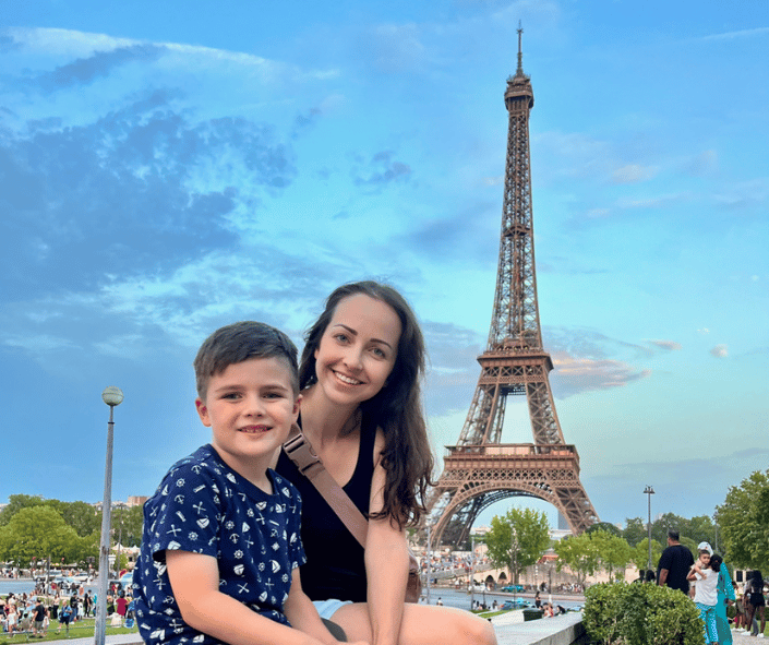 A mom and son sit together in front of the Eiffel Tower