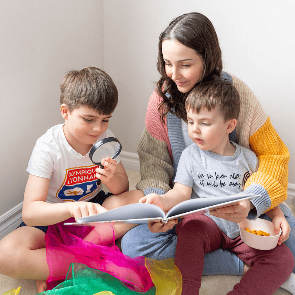 Madame Amy reading a book with her two sons during a French learning moment at home